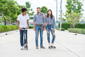 Group of multi-ethnic friends, an African American teenager on a scooter, an Asian woman on a...