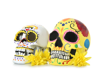 Painted human skulls for Mexico's Day of the Dead (El Dia de Muertos) and flowers on white background