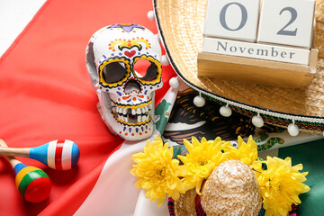 Painted human skull for Mexico's Day of the Dead (El Dia de Muertos), maracas, flowers and sombrero on flag