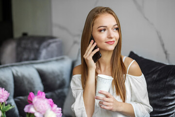 Young smiling woman talking on cell phone at home