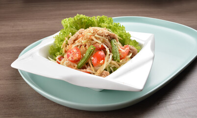 thai cold mango papaya vegetable salad in spicy sour lime sauce on wood background asian halal vegan menu