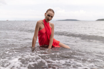 Beautiful woman in a red dress on a beach.
