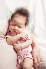 a baby girl in the arms of her mother, on a light background