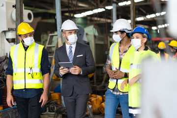 Engineers people are brainstorming solving problems of heavy industrial machinery. Worker man and asian woman wearing face mask prevent covid-19 virus and protective hard hat. .