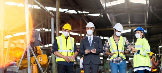 Engineers people are brainstorming solving problems of heavy industrial machinery. Worker man and asian woman wearing face mask prevent covid-19 virus and protective hard hat. .