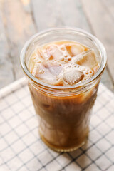 Glass of ice coffee on wooden background, closeup