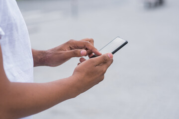 Close up of hands of African American man with a smartphone. Freelance, working, touching, typing