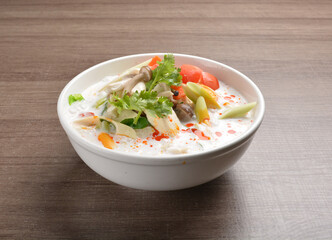 cook hot and spicy white coconut curry laksa soup with mushroom and mixed vegetables in white bowl on wood background asian halal vegan menu