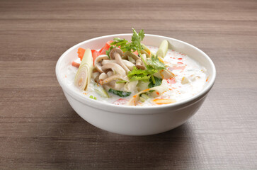cook hot and spicy white coconut curry laksa soup with mushroom and mixed vegetables in white bowl on wood background asian halal vegan menu