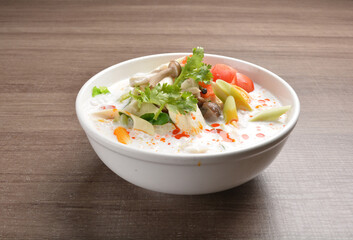 cook hot and spicy white coconut curry laksa soup with mushroom and mixed vegetables in white bowl on wood background asian halal vegan menu