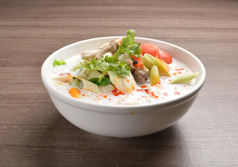 cook hot and spicy white coconut curry laksa soup with mushroom and mixed vegetables in white bowl on wood background asian halal vegan menu