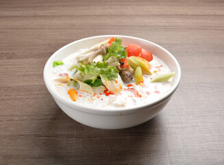 cook hot and spicy white coconut curry laksa soup with mushroom and mixed vegetables in white bowl on wood background asian halal vegan menu