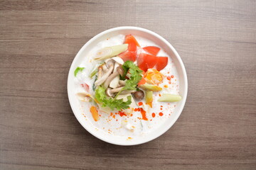 cook hot and spicy white coconut curry laksa soup with mushroom and mixed vegetables in white bowl on wood background asian halal vegan menu