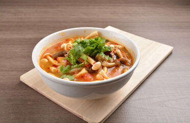 cook hot and spicy tom yum soup with mushroom and mixed vegetables in white bowl on wood background asian halal vegan menu