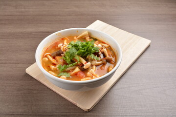 cook hot and spicy tom yum soup with mushroom and mixed vegetables in white bowl on wood background asian halal vegan menu