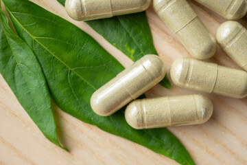 Fototapeta na wymiar Herbal medicine capsules with Andrographis paniculata leaf on wood table
