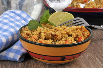 Taboulé au curry avec une rondelle de citron et des feuilles de menthe servi dans un bol