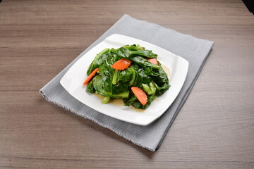 stir fried kai lan vegetable and carrot in soy sauce on wood background asian halal vegan menu
