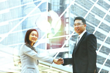 Asian business man woman hand shake join company with worker signature online on laptop blur building background