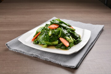 stir fried kai lan vegetable and carrot in soy sauce on wood background asian halal vegan menu