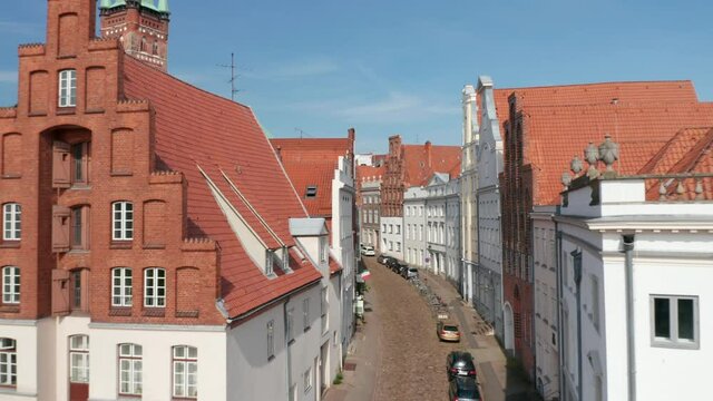 Forwards fly through historic curved street in medieval city centre. Old houses with beautiful and well-maintained facades. Luebeck, Schleswig-Holstein, Germany