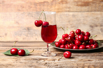 Glass of sweet cherry wine on wooden background