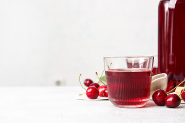 Glass of sweet cherry wine on light background, closeup