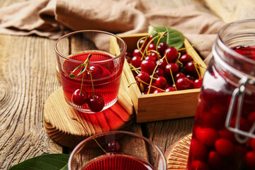 Glass of sweet cherry wine on wooden background