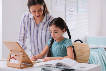 Mother helping her daughter doing homework with tablet at home