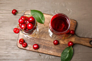 Naklejka na ściany i meble Glass of sweet cherry and wine on wooden background