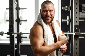 Cheerful smiling man bodybuilder standing in a gym