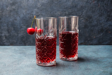 Glasses of sweet cherry wine on dark background