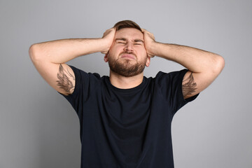 Man suffering from migraine on grey background