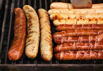 delicious variety of sausages on the grill grill over an open fire. Food festival in the city on the street. sausages are grilled at the food court barbecue for a summer picnic. Grilled Munich sausage