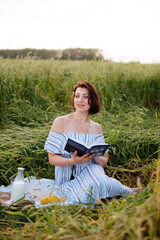 Naklejka na ściany i meble Beautiful young woman in summer in a wheat field