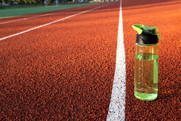 Bottle of water on the red running road.Natural sunrise light.Empty space