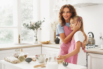 Portrait of a teen girl with her mother at home in kitchen