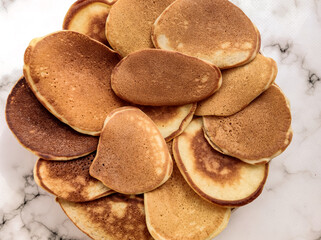 a lot of delicious appetizing pancakes with sour cream large plate on a white table top view