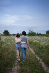 Fototapeta premium young loving couple embracing strolls in the evening in the picturesque flowering fields. boy and girl, tender feelings, romance, tenderness for each other. love concept. healthy active lifestyle