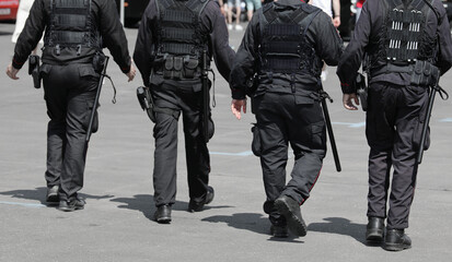 patrol of 4 policemen with truncheons and guns that control the city