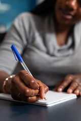 Closeup of black student hands writing university homework during online communication lesson...