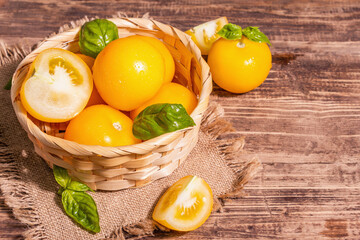 Ripe yellow tomatoes with fresh basil in a wicker basket