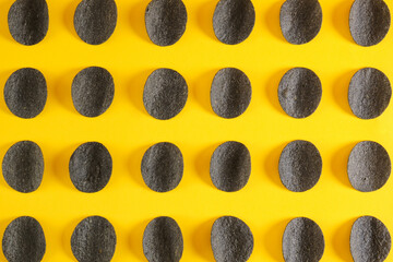 Fototapeta na wymiar pattern of black potato chips on a yellow background, copy space, chips made from natural ingredients, trend snack