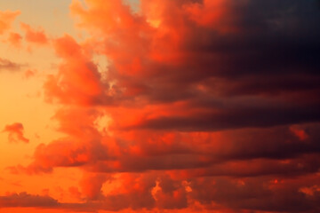 Red orange yellow epic dramatic scary mystical sunset sky with black clouds before thunderstorm storm, bright fantastic colorful sky landscape background