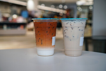 Iced Thai Tea and Milk tea. Two plastic cup on white table at drink cafe.