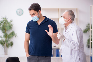 Young male patient visiting old male doctor during pandemic