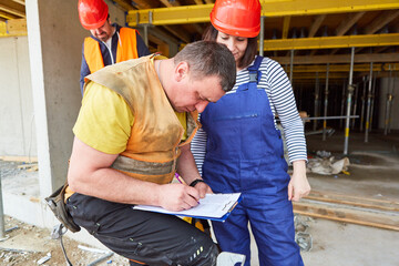 Handwerker mit Checkliste oder Protokoll auf Baustelle