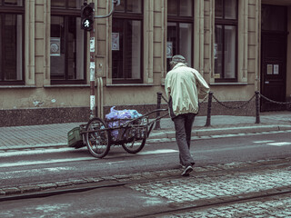 Obraz premium man pushing a cart with loads, street photography