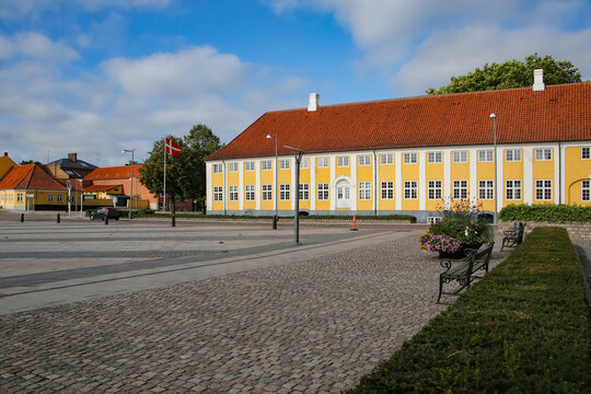 Kaalund Monastery is located in Kalundborg Municipality, Denmark. Historic yellow and white building with plaque above the door and town square in front.