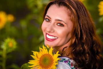 Beautiful woman enjoying nature in the sunflower field at sunset. Traditional clothes. Attractive brunette woman with long and healthy hair.